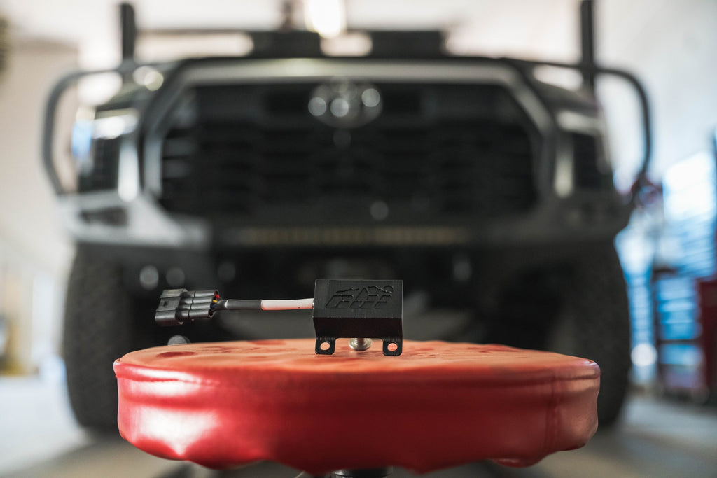 CBI Offroad 2022-2025 Tundra Front Active Spoiler Delete Module on a red stool in front of a Tundra truck.